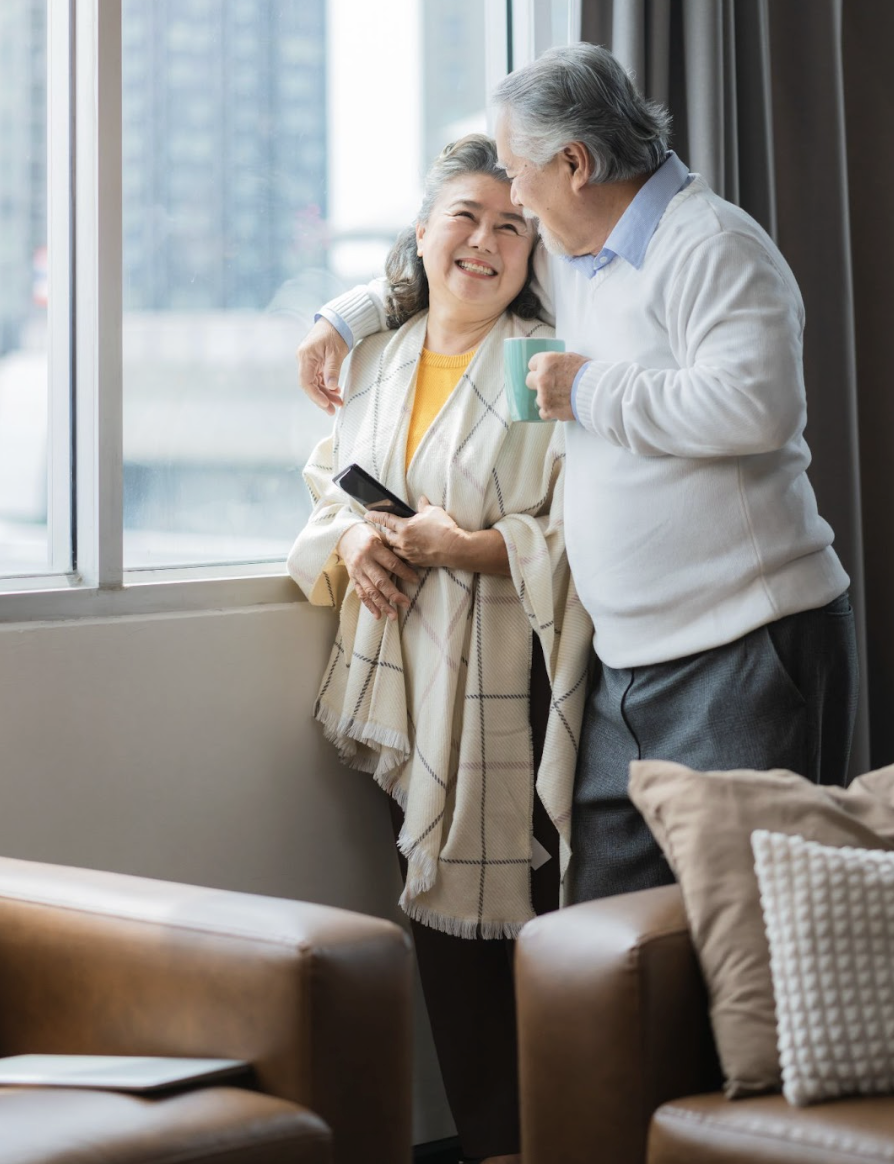 Happy couple in their new apartment overlooking the city after downsizing from their suburban home